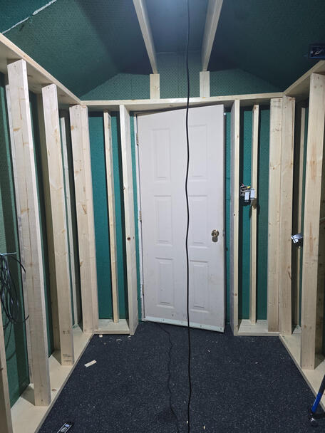 Small empty room with visible framing studs and door